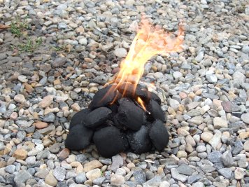 A small pile of charcol briquets with flame